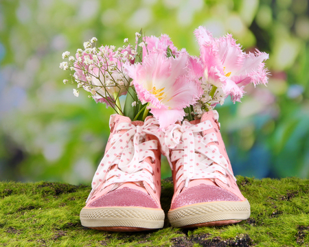 Beautiful gumshoes with flowers inside on green grass, on bright backgroundの写真素材