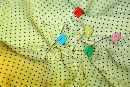 Safety pins on fabric background