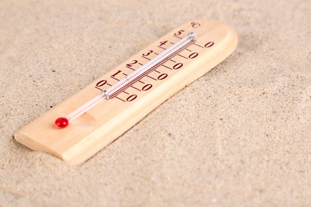 Thermometer on sand background