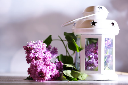 Beautiful lilac flowers in vase, on color wooden table, on dark backgroundの写真素材