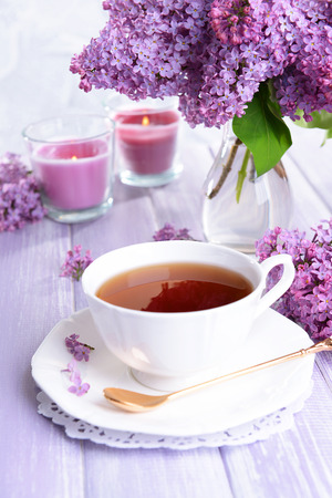 Beautiful lilac flowers with cup of tea on table close-upの写真素材