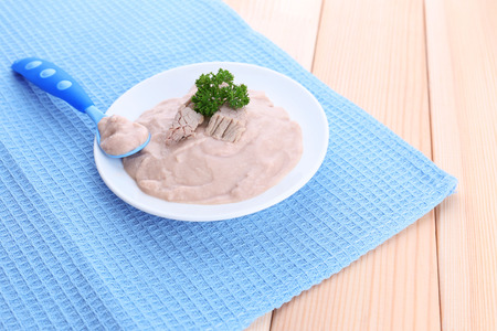 Meat paste for infant feeding, on plate, on wooden backgroundの写真素材