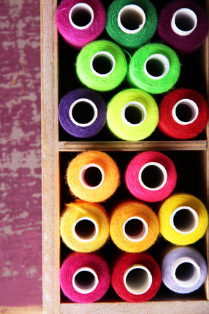 Multicolor sewing thread in wooden box, on wooden background, close-upの写真素材