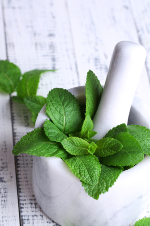 Fresh green mint in mortar on color wooden backgroundの写真素材