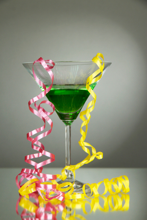 Glass of cocktail and streamer after party on gray backgroundの写真素材