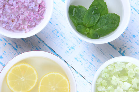 Aromatherapy treatment bowl with flowers and perfumed water on wooden backgroundの写真素材