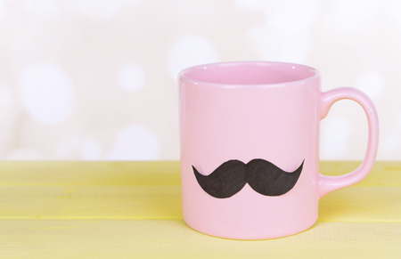 Cup with mustache on table on light backgroundの写真素材