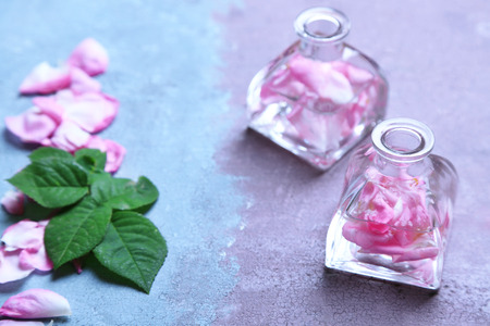 Rose oil in bottles on color wooden backgroundの写真素材