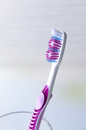 Toothbrush in glass on table on light backgroundの写真素材