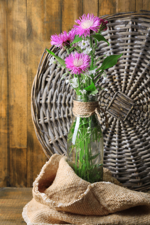 Bright wildflowers in bottle on wooden backgroundの写真素材