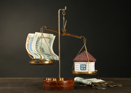 Scale with money and model of house on dark backgroundの写真素材