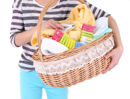 Woman holding laundry basket with clean clothes, towels and pins, isolated on whiteの写真素材