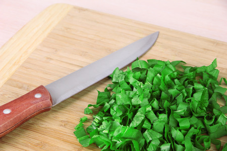 Chopped greens with knife on cutting boardの写真素材