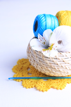 Colorful clews and crochet hooks in wicker basket on wooden backgroundの写真素材