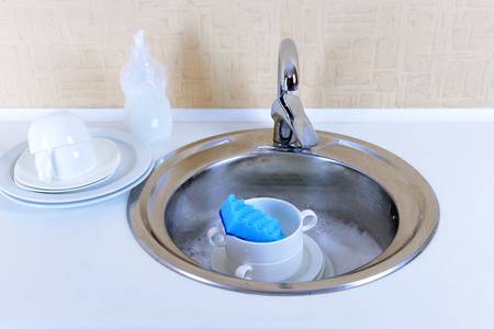 Stack of dishes soaking in kitchen sinkの写真素材