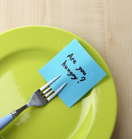 Note paper with message  attached to fork, on plate, on wooden backgroundの写真素材