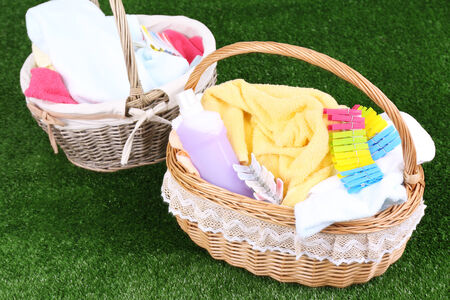 Colorful towels and clothes in baskets on green grass backgroundの写真素材