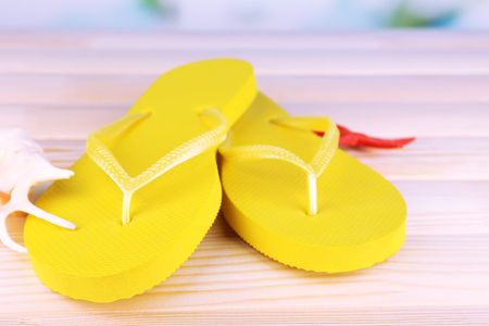 Bright flip-flops on wooden table, on nature backgroundの写真素材