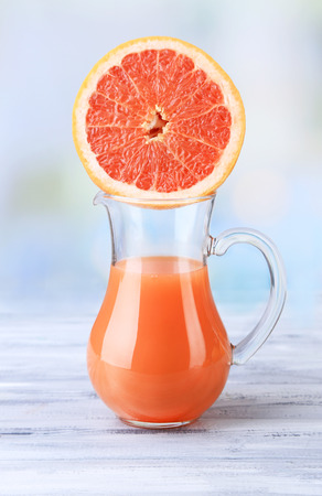 Grapefruit juice in glass jug on color wooden backgroundの写真素材