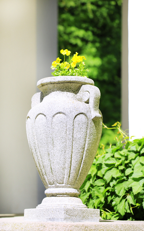 Stone planter with flowers near driveway of houseの写真素材