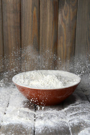 Flour in bowl on table on wooden backgroundの写真素材