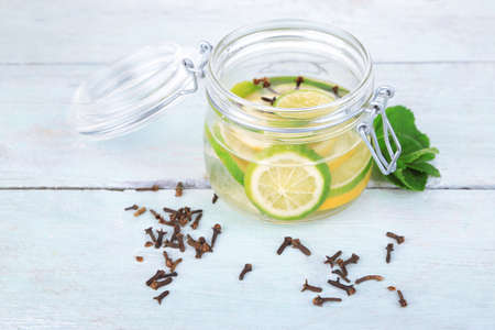 Pickled limes and cloves in glass jar, on color wooden backgroundの写真素材