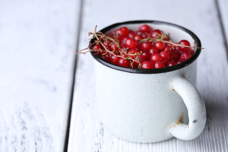 Red currant berries in mug on wooden backgroundの写真素材