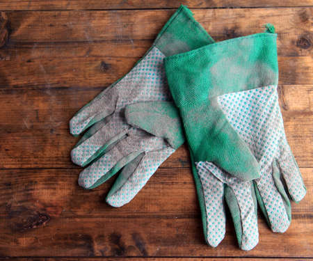 Dirty used fabric gloves on wooden backgroundの写真素材