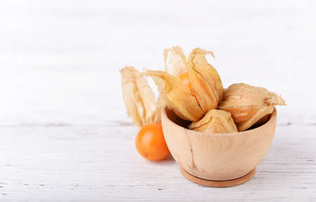 Physalis fruits in wooden bowl on wooden backgroundの写真素材