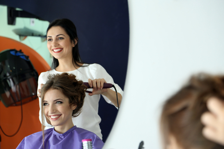 Young woman hairdresser do hairstyle girl in beauty salonの写真素材