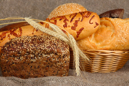 Baked bread in wicker basket on burlap background