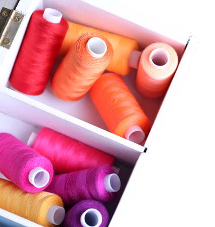 Multicolor sewing thread in wooden box, close-up, isolated on white
