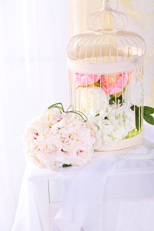 Beautiful wedding bouquet and birdcage on table on light backgroundの写真素材
