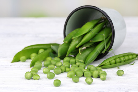 Fresh green peas in metal cup on wooden tableの写真素材