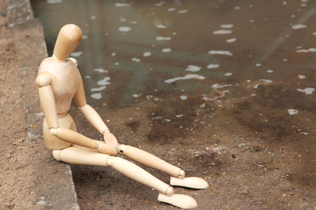 Wooden pose puppet sitting on stone, outdoorsの写真素材