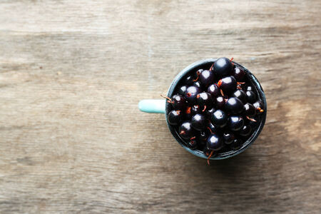 Black currant berries in mug on wooden backgroundの写真素材