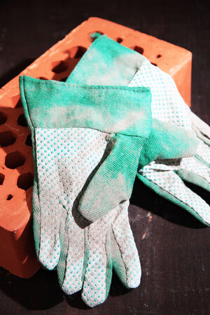 Dirty used fabric gloves and bricks on wooden backgroundの写真素材