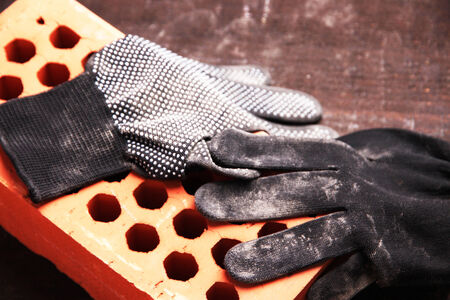 Dirty used fabric gloves and bricks on wooden backgroundの写真素材