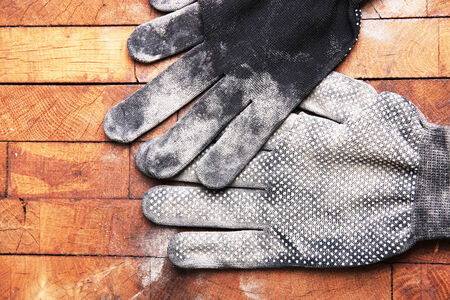 Dirty used fabric gloves on wooden backgroundの写真素材
