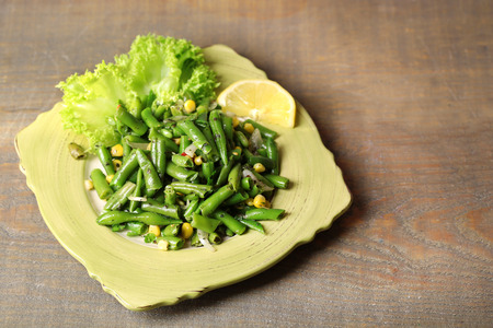 Salad with green beans and corn, on plate, on color wooden backgroundの写真素材