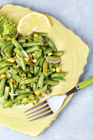 Salad with green beans and corn, on plate, on color wooden backgroundの写真素材