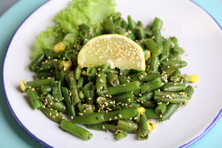 Salad with green beans and corn, sesame seeds on plate, on color wooden backgroundの写真素材