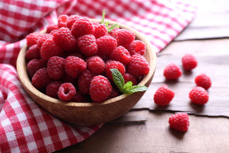 Ripe sweet raspberries in bowl on table close-up