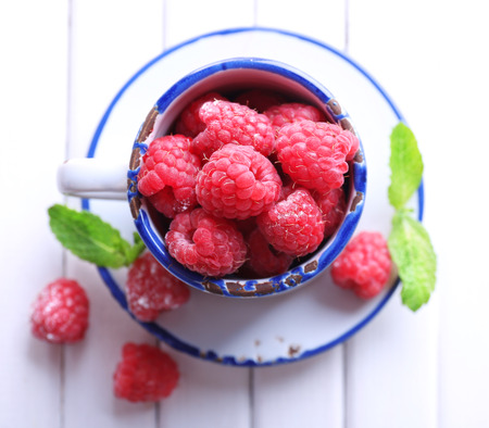Ripe sweet raspberries in cup on table close-upの写真素材