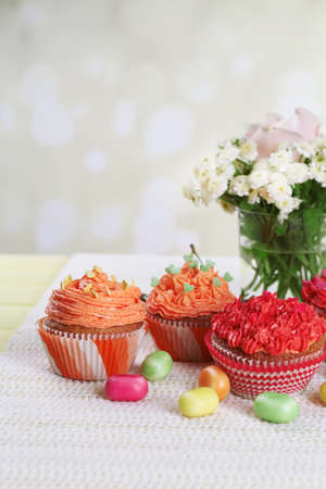 Tasty cupcakes on table, on bright background