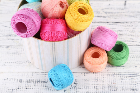 Clews of thread for hook knitting in box on wooden background