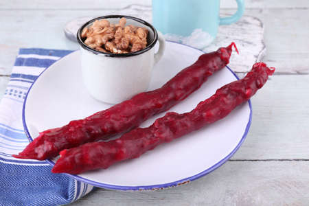Tasty oriental sweets (churchkhela) and fresh nuts, on  plate, on wooden backgroundの写真素材