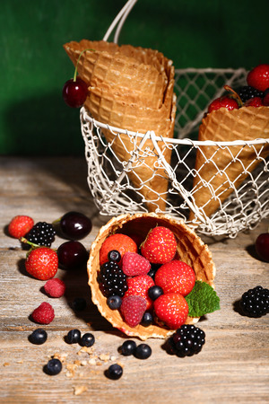 Different ripe berries in sugar cones, on wooden backgroundの写真素材