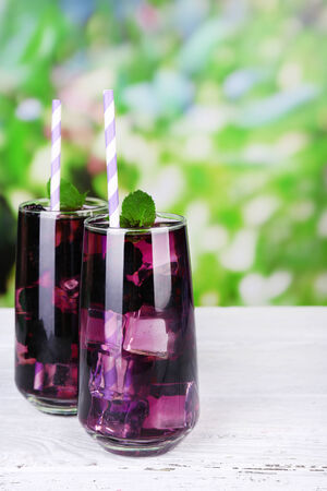 Tasty cool blackberry lemonade with ice on wooden table, on nature backgroundの写真素材