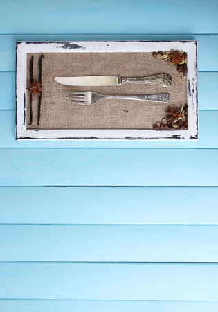 Wooden frame, spices and vintage cutlery  on color wooden backgroundの写真素材